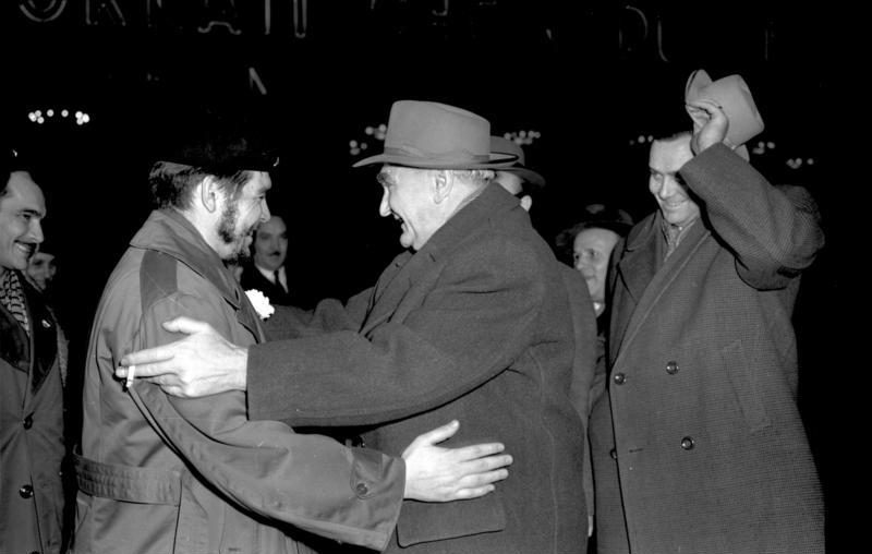 Ernesto Guevara, de uniforme e boina, cumprimenta Heinrich Rau num aeroporto.