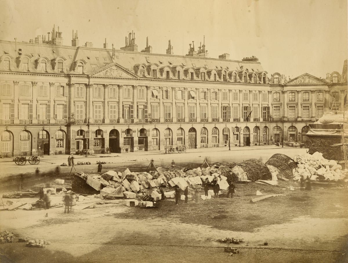 A Coluna Vendôme derrubada no chão da praça, cercada por guardas nacionais e curiosos.