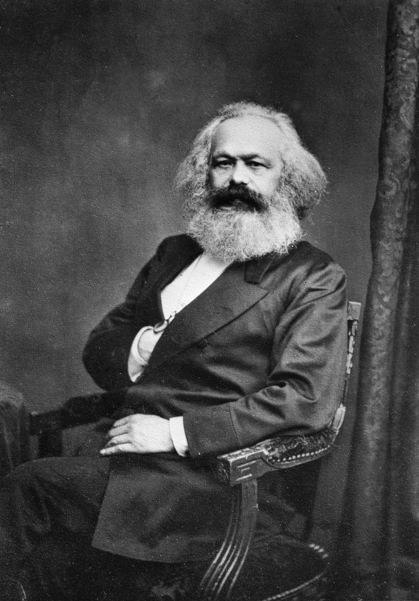Fotografia em preto e branco de Karl Marx, de barba e cabelos brancos, vestindo sobrecasaca.