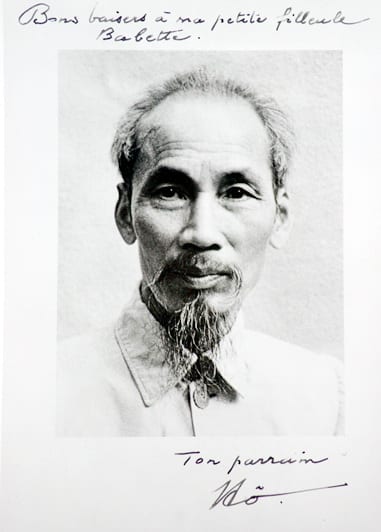Retrato em preto e branco de Ho Chi Minh, de barba rala, com dedicatória manuscrita em francês.